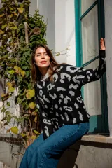 Buzo de punto color negro con estampado animal print en gris claro, de corte holgado y manga larga.