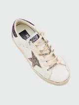Championes Golden Goose modelo Hi Star, color blanco con detalles en glitter color lila en el talón y en la estrella lateral.
