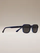 Lentes de sol negros con marco cuadrado y lentes azules degradados.