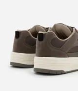 Championes de estilo urbano, color beige claro, con cordones gruesos trenzados y suela ancha de plataforma en tonos crema y gris. Presenta recortes en material sintético liso y gamuzado.