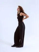 Pantalón de jean negro de corte wide leg con tachas plateadas en los laterales.