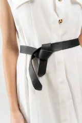 Cinturón de cuero negro, delgado y liso, con terminación en lazo.