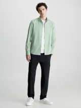 Camisa verde claro de popelín elástico, corte slim, con cierre frontal de botones, mangas largas y logo de Calvin Klein bordado en el pecho.