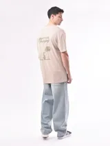 Remera beige de corte holgado con estampado de texto en el pecho.