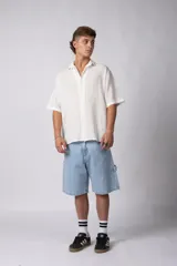 Camisa de lino color blanco, de manga corta, con cuello clásico y cierre frontal con botones.