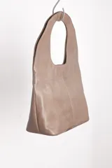 Bolso tote negro de cuero con manija circular rígida.