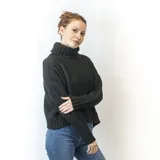 Sweater tejido color crudo, con cuello alto y diseño de trenzas verticales en el frente.