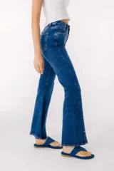 Pantalón de jean azul de corte acampanado con aberturas en el ruedo.