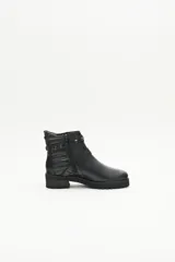 Bota de cuero negra con caña media, tiras cruzadas con hebillas y remaches metálicos, laterales matelaseados y cierre lateral interno.