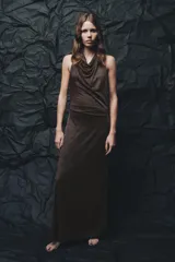 Vestido largo de fiesta confeccionado con hilo metalizado color marrón. Tiene cuello halter con lazada, escote drapeado, espalda descubierta con tira ajustable y cierre lateral con cremallera oculta.