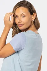 Remera de manga corta y cuello redondo, con bloque de color: cuerpo color crema, manga derecha color rosa y manga izquierda color celeste.