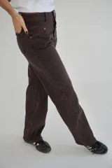 Pantalón de jean marrón de corte recto y tiro medio, con costuras en color naranja y texto estampado en el bolsillo trasero.