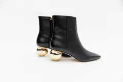 Botas cortas de cuero negro con punta fina y cierre lateral. Taco dorado con forma de esfera.