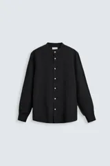 Camisa negra de corte relaxed fit, confeccionada en tejido de lino y algodón. Tiene cuello mao, manga larga con puños abotonados y cierre frontal con botones.