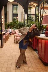 Blazer oversize con diseño asimétrico que combina dos tweeds contrastantes, uno a rayas beige y otro liso marrón. Presenta botones de strass y un pin de salchicha.