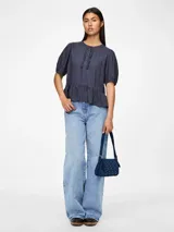 Blusa azul de mangas 3/4 con cuello redondo, botones y volantes.