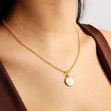 Collar dorado con cadena fina y dije redondo con el signo zodiacal de Leo.