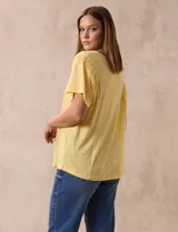 Remera amarilla de lino y poliéster, manga corta con fruncido en los hombros y escote redondo.