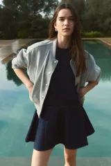 Vestido corto sin mangas en denim azul, con escote redondo y cierre oculto en la espalda. Costura visible en la cadera y pollera acampanada con nesgas para dar vuelo.