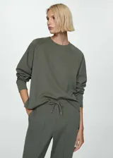 Jersey verde oscuro de tejido fluido con cuello redondo y manga larga.