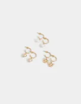 Set de tres pares de aros argolla dorados con dijes colgantes: corazón con perla, mariposa calada y corazón liso.