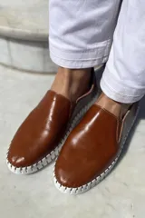 Slippers de cuero celeste con elásticos laterales y suela de goma blanca.
