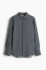Camisa de manga larga con cuello, botones adelante y canesú con pliegue de caja en la espalda. Modelo de manga larga con puños abotonados y tapeta con botón. Bajo redondeado.
