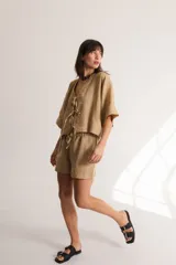 Blusa color crema confeccionada en lino, con mangas cortas, escote en V y lazos frontales.