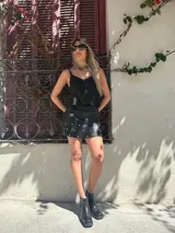 Minifalda negra de cuero sintético con volados y tachas plateadas.