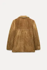 Blazer marrón de piel de ante, con cuello solapa, manga larga, bolsillos delanteros con solapa, forro interior a tono, abertura en la espalda y cierre frontal con botones.