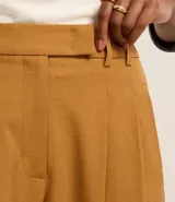 Pantalón de vestir color ocre, de corte recto, con cintura alta, bolsillos laterales y pinzas delanteras.