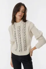 Sweater tejido color crudo con cuello redondo y mangas largas. Presenta detalles de ochos en el frente y está confeccionado artesanalmente en Uruguay.