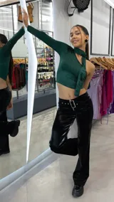 Pantalón negro de eco cuero, tiro bajo y corte wide leg con cinturón con hebilla metálica.