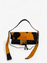 Cartera bandolera color gris con solapa de pelo blanco con estampado de círculos marrones. Cierre con botón magnético y herraje metálico plateado en forma de "S".