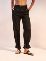 Pantalón negro de lino con corte recto, cintura alta y detalle de lazos en los tobillos.