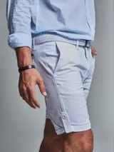 Bermuda color beige con cinturón, corte regular fit, dos bolsillos delanteros, dos traseros, un bolsillo relojero y botamanga con presilla. Aplique de badana.