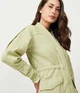 Campera parka color verde claro, de corte holgado, con cuello en V, bolsillos delanteros y puños abotonados.