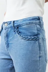 Jean bootcut de tiro medio, color celeste claro, con detalle trenzado en los bolsillos delanteros y traseros.