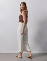 Pantalón de lino color crudo, de corte ancho y tiro alto, con bolsillos laterales y cintura elástica.
