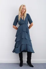 Vestido azul petróleo con escote en V, largo midi, mangas cortas, elástico en la cintura y falda con volados en capas.