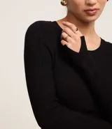 Suéter negro de punto acanalado con mangas largas y cuello redondo.
