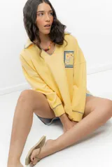 Buzo amarillo de algodón con cuello polo, mangas largas y bordado de un sello con motivos marinos.