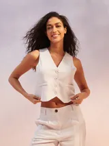 Chaleco color beige claro, de corte sastre y escote en V, con cierre frontal de botones y bolsillos delanteros.