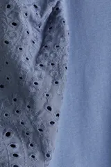 Top azul de punto de algodón con cuello redondo y bajo recto. Mangas globo cortas en tejido de algodón con forro de punto y ribete elástico.