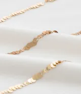 Remera de viscolycra color crudo, de corte regular, con cuello redondo, mangas cortas y apliques de lentejuelas verticales.