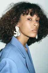 Aros colgantes con forma de abanico realizados en resina color crema con borde negro. Cierre con tuerca y clip.