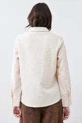 Camisa beige de manga larga con textura fantasía.