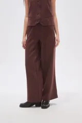 Pantalón de poliéster color marrón con rayas verticales finas en blanco, de corte ancho y tiro medio. Incluye bolsillos laterales.