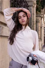 Blusa color crema de cuello alto con detalles en los puños.