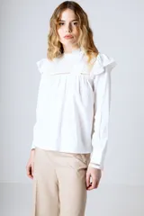 Blusa blanca de mangas largas con cuello alto con volados y detalles de encaje.